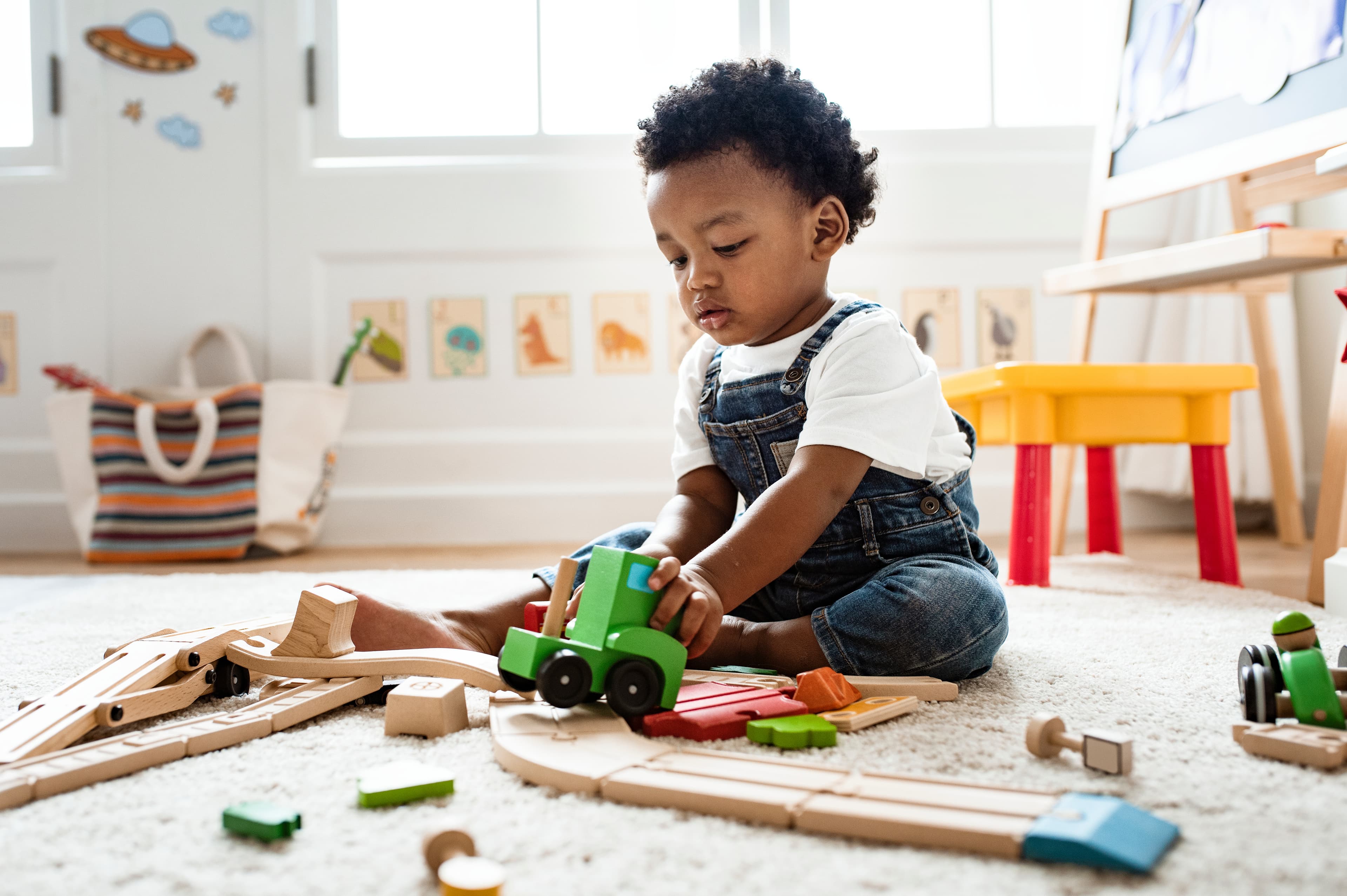 Young child exploring a wooden train and tracks during hands-on play